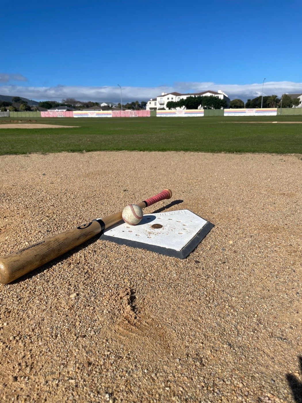 Home plate, bat, and ball on the field at Abe Sher Stadium, Bothasig Baseball Club